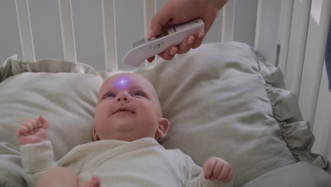 Unrecognizable-woman-measuring-temperature-to-a-crying-baby