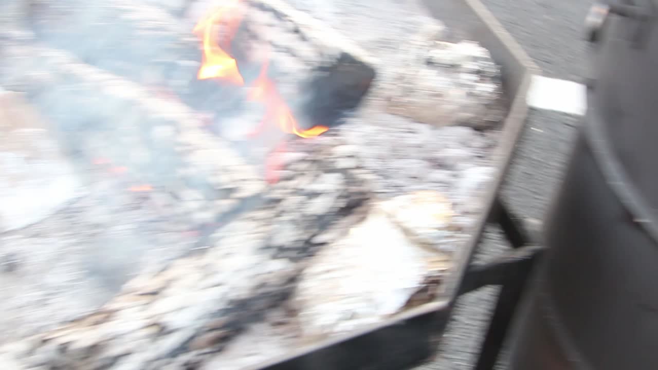 검은색 요리 드럼에서 불 포커를 다루는 요리사, 그가 방금 은 석탄과 배럴 에 있는 다른 불 구이를 보기 위해 배럴의 위아래로 이동합니다.