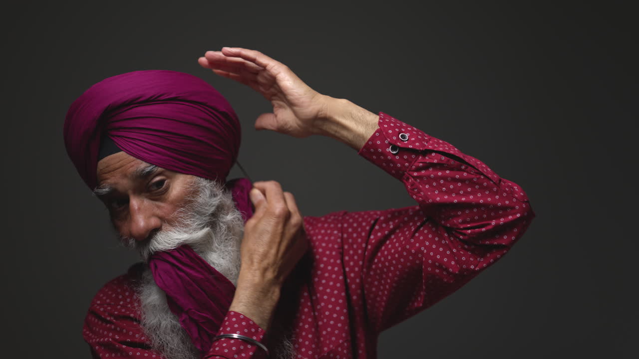 Close Up Low Key Studio Lighting Shot Of Senior Sikh Man With Beard Using Salai Needle When Putting On Turban Against Dark Background Shot In Real Time 2