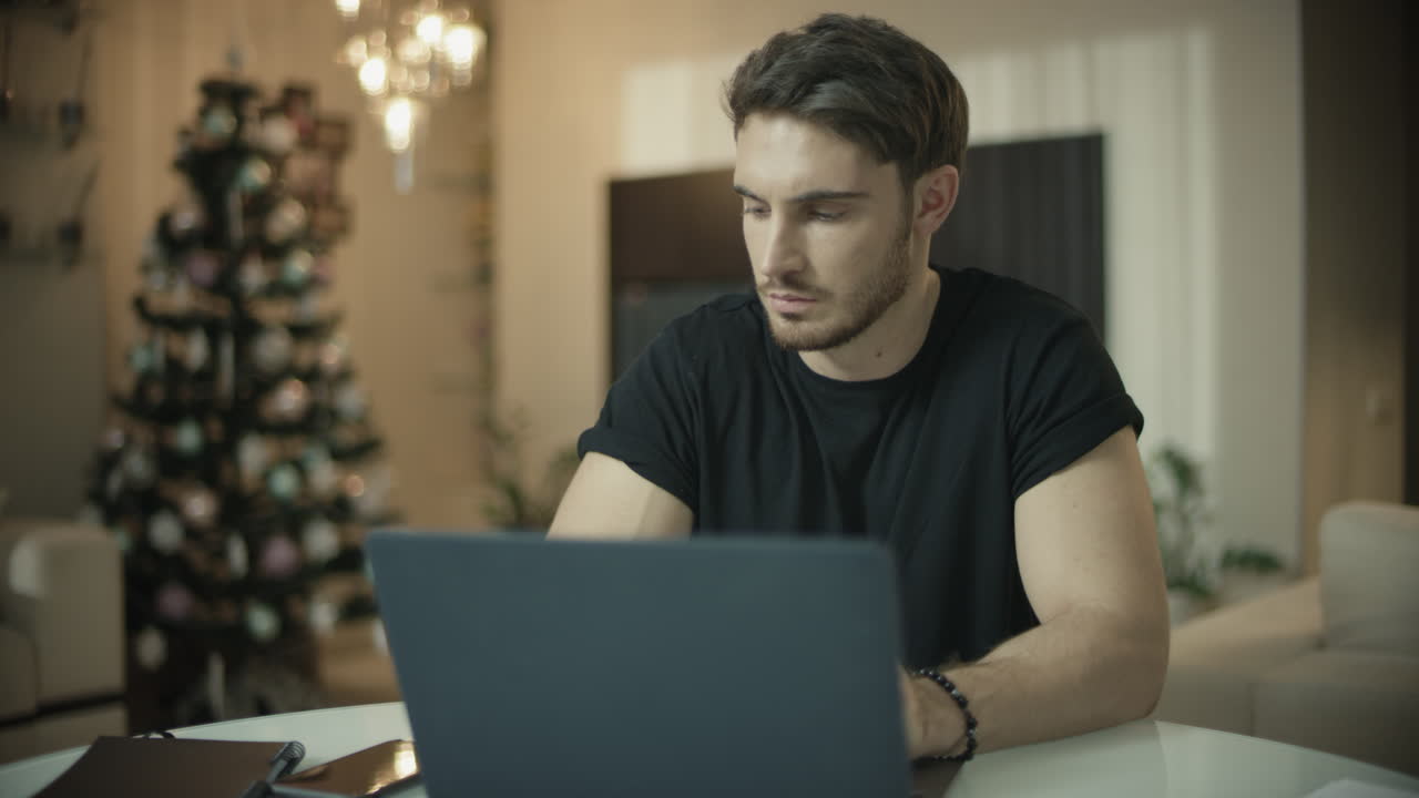 Serious man talking phone at christmas home. Male guy working on computer desk