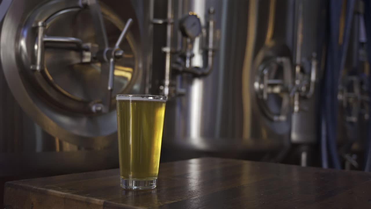 Close up of a beer glass with stainless steel tanks on the background