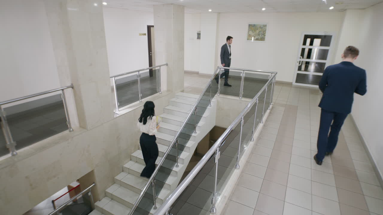 People walking and interacting in a modern office building hallway and staircase