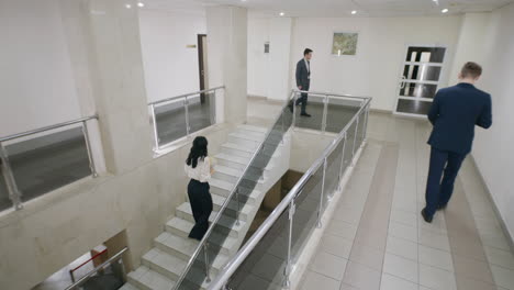 people walking and interacting in a modern office building hallway and staircase