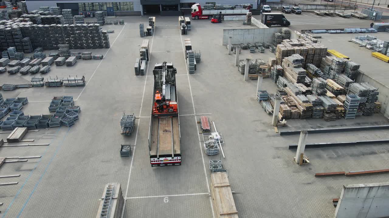 Beautiful aerial of a large truck on an industrial storage yard loading the with a onboard crane