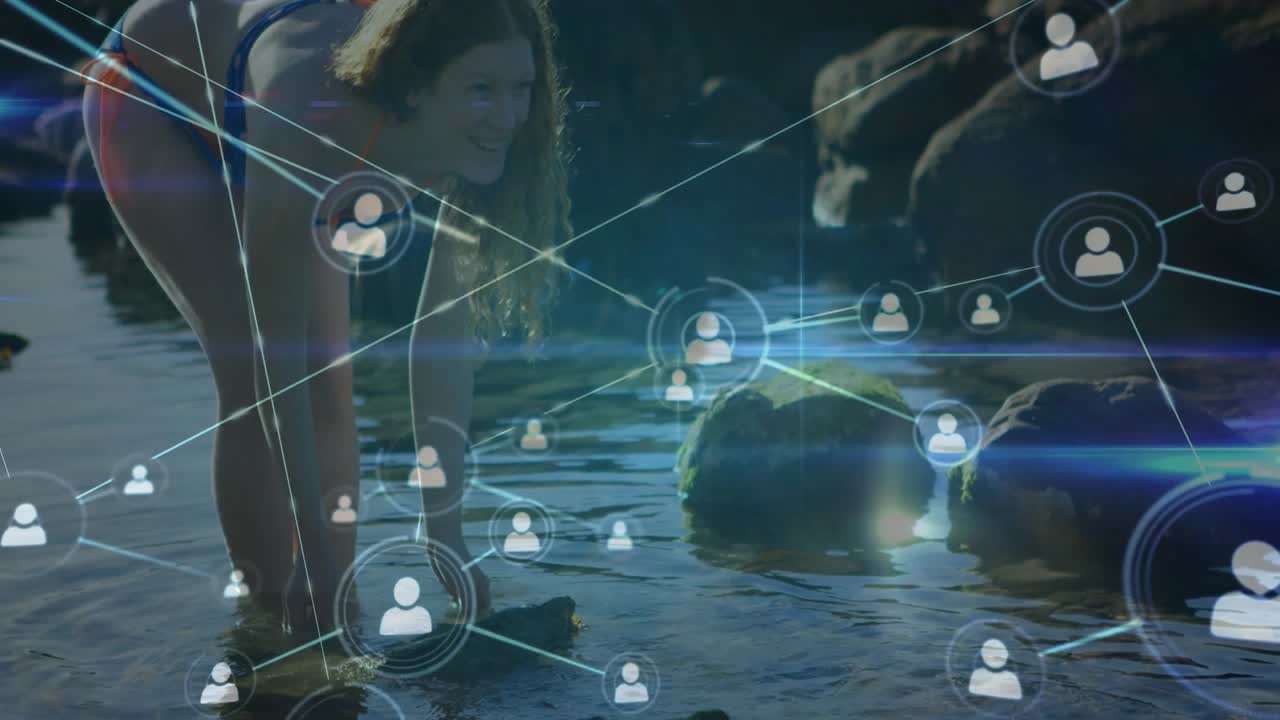Woman wading on rock, reaching into water and creating splash, causing technology network overlay
