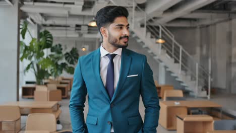 young manager standing in a modern office, hands in pockets, smiling confidently while planning new strategies in an elegant suit and tie