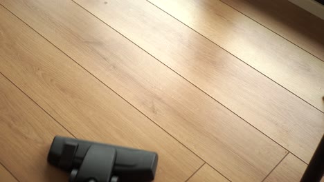 close up shot of a vacuum cleaner cleaning a wooden floor.