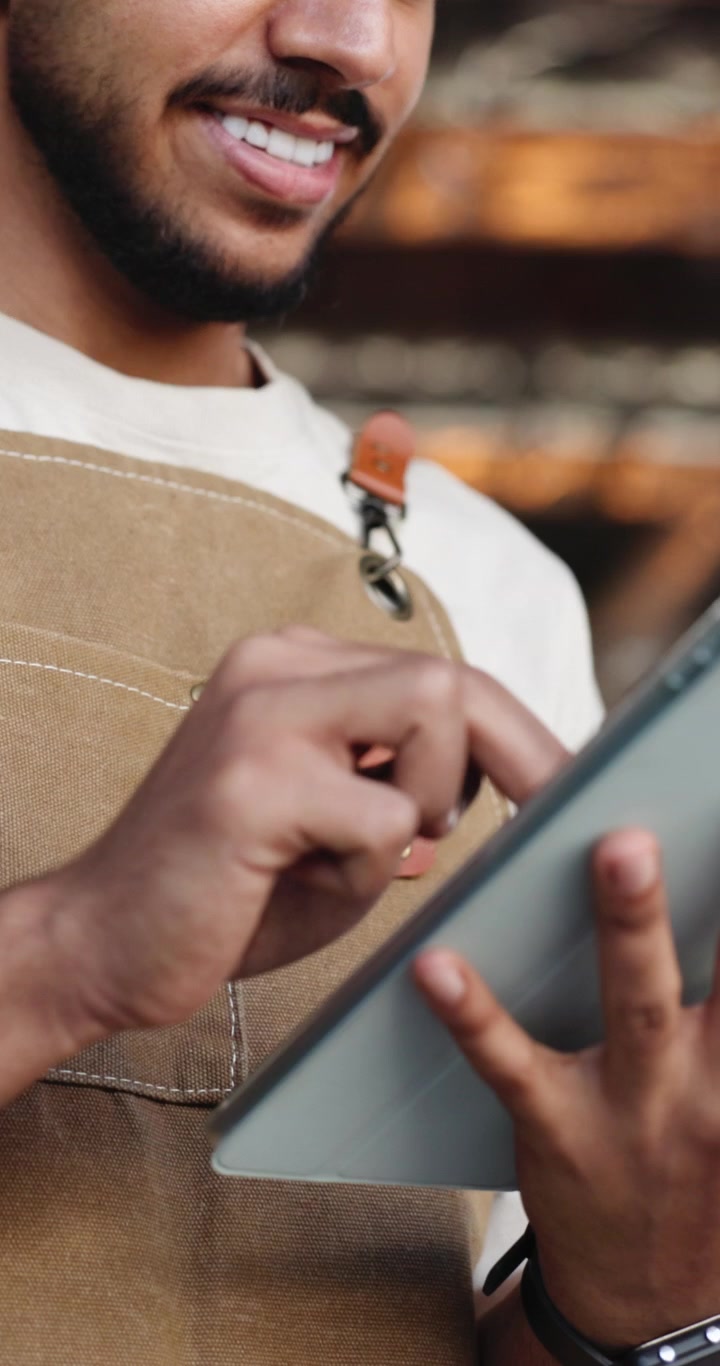 Smiling Barista Using Digital Tablet in Coffee Shop