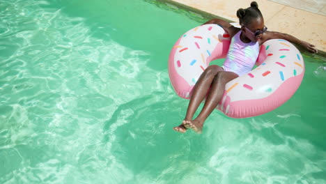 smiling girl relaxing on donut float in swimming pool, enjoying sunny day