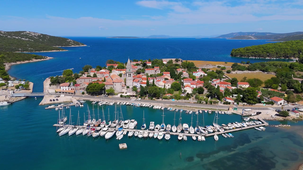 Panorama della città di Osor sull'isola di Cherso, Croazia, in una splendida giornata estiva. Le viste aeree mostrano il centro storico, spiagge soleggiate, yacht a vela, il porto turistico e campeggi vicini sulla costa adriatica mediterranea
