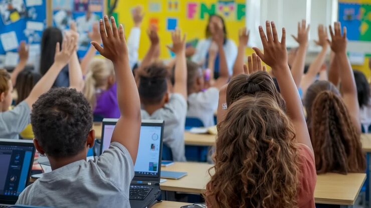 Teacher wearing dress asking question in classroom, kids raising and lowering hands to volunteer