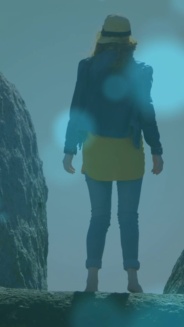 Animation of glowing spots over caucasian woman standing on rock