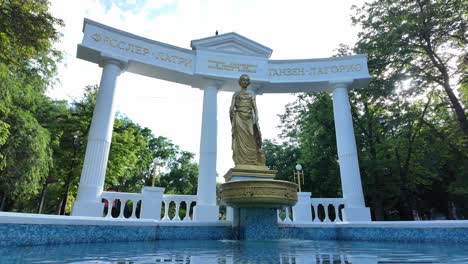 una hermosa fuente con una estatua de una mujer en el medio de un parque en un día soleado