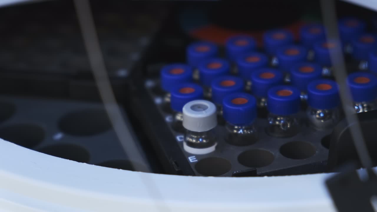 Scientist in rubber gloves puts HPLC vials into the auto sample for measuremetns