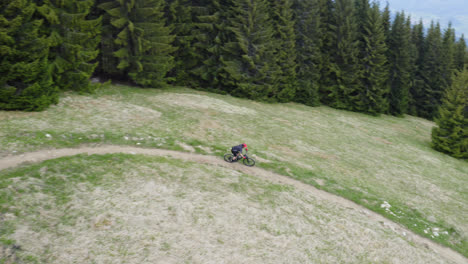 A-Young-Biker-Riding-On-A-Curved-Path-In-Green-Hill-Landscape-At-Malino-Brdo-Resort,-Ruzomberok,-Liptov,-Slovakia