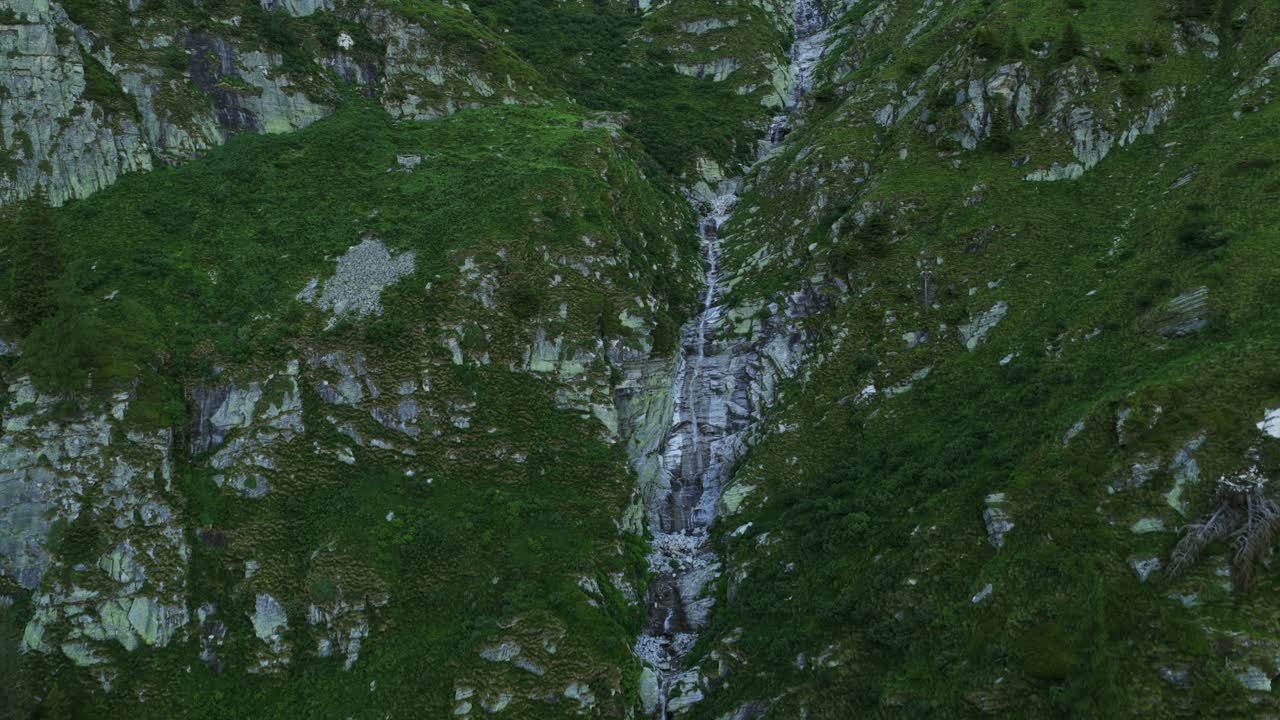 Antrona Alps waterfall flows over rugged rocks and green vegetation