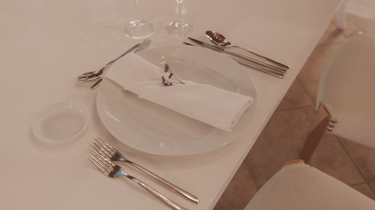 Tavola apparecchiata bianca con piatto di tovagliolo piegato e posate in argento