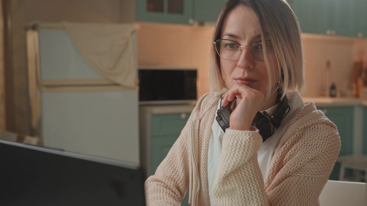 Women brainstorming and designing ideas. Thoughtful woman working on artistic projects. An engaged woman is sketching innovative ideas while wearing headphones in warm kitchen environment