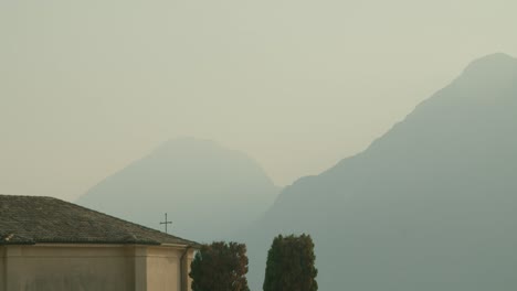 Toma-Completa,-Cruz-En-La-Parte-Superior-De-Una-Iglesia-En-Malcesine,-Atardecer-Y-Puesta-De-Sol-En-El-Fondo