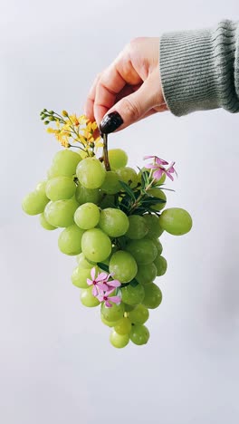 hand holding a bunch of green grapes decorated with flowers