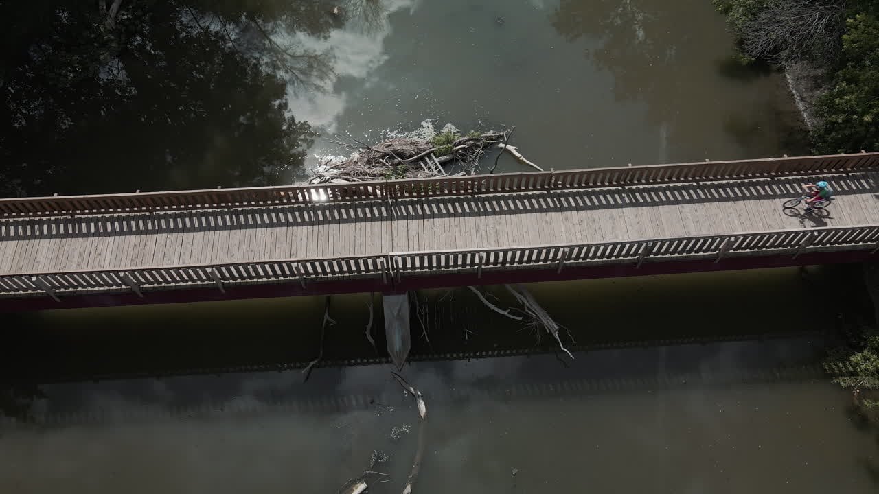 화창한 날씨에 자전거로 나무 다리를 건너는 남자