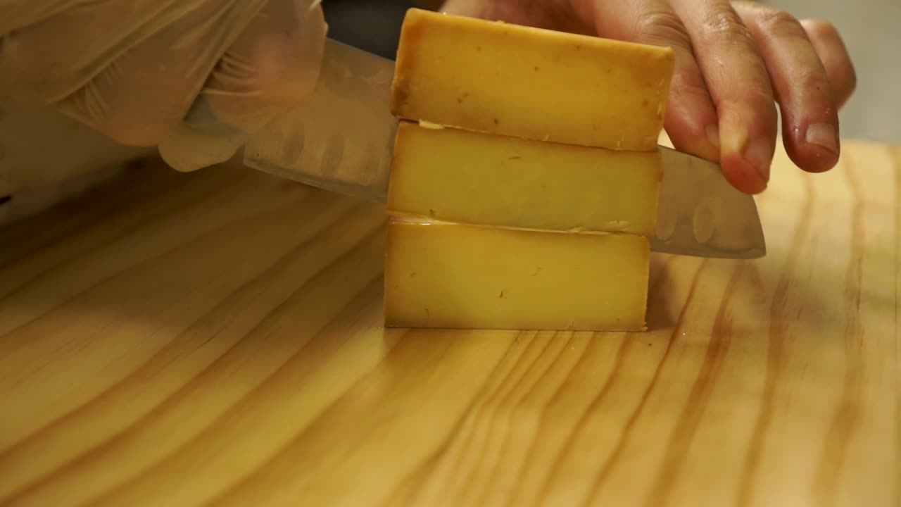 chef en el restaurante de la cocina rebanando queso vintage en una tabla de cortar de madera - cerca de las manos