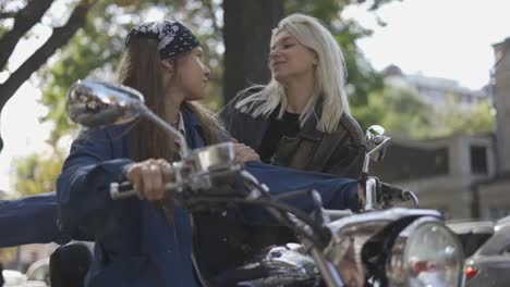 girl kissing her girlfriend from mounted motorcycle in the city