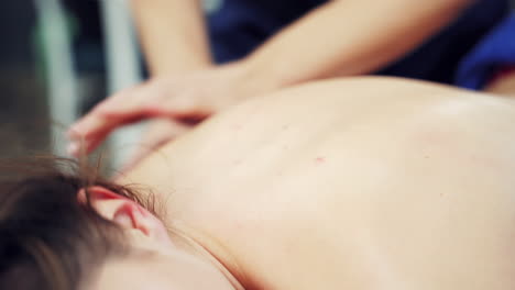 therapist's hands doing healthy massage on the female's back outside. young woman relaxing while receiving body massage. close-up