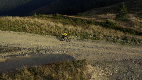 Aerial-mountain-road-cycling-view-man-biking-among-spring-grass-sunny-day