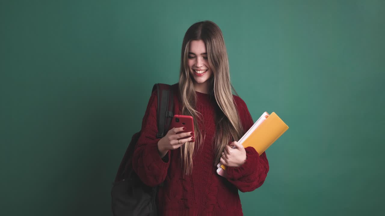 Giovane studentessa in piedi con libri e smartphone