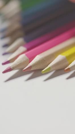 Vertical-Video-Studio-Shot-Of-Multi-Coloured-Pencils-In-A-Line-On-White-Background-With-Hand-Choosing-