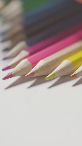 fotografía vertical de estudio de vídeo de lápices multicolores en una línea sobre fondo blanco con selección a mano