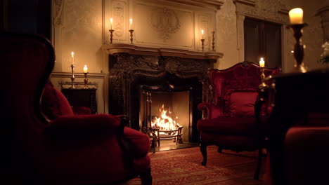luxurious sitting room with burning fireplace, red armchairs, and lit candles