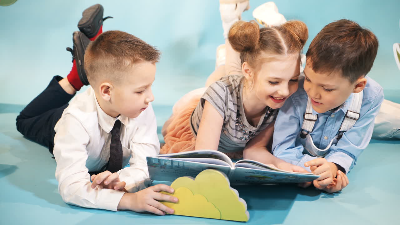 Bambini curiosi leggono un libro insieme. Infanzia felice. Servizio fotografico in studio di bambini.