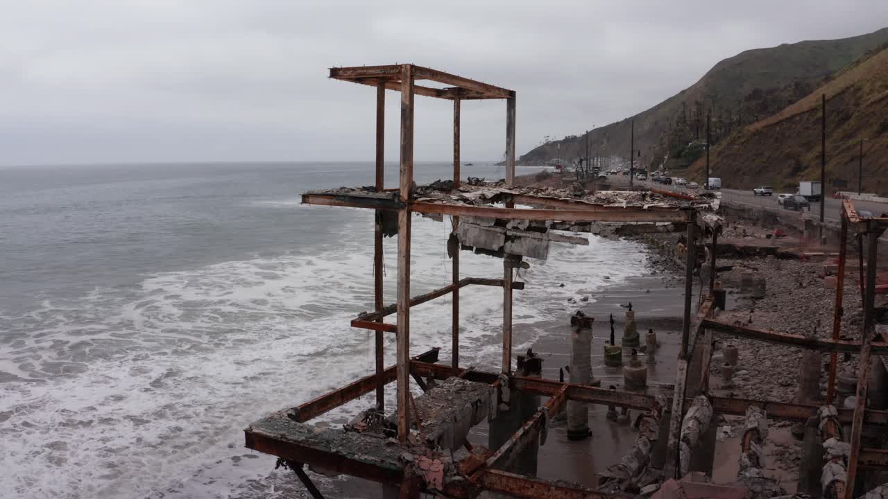 Aerial rising close-up shot of an oceanfront home burned by the Palisades Fire in Malibu, California. 4K