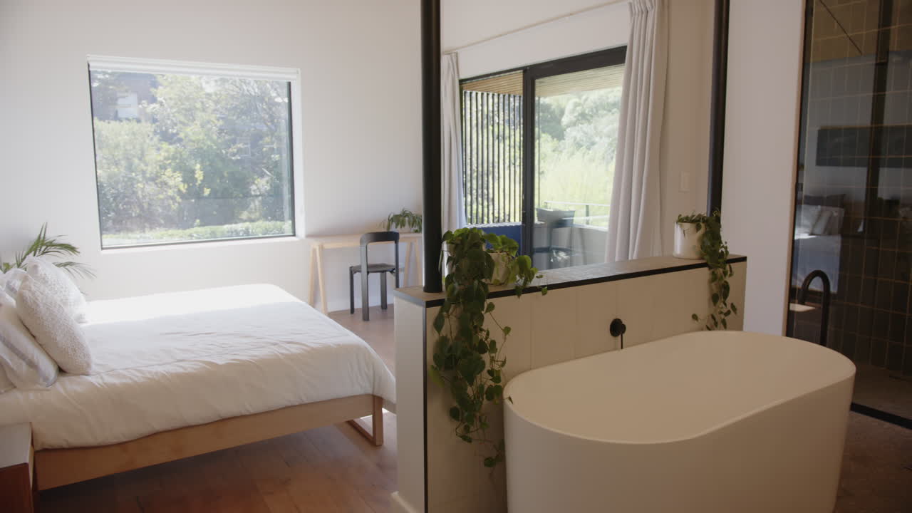 Freestanding bathtub in modern bedroom with large window, creating serene atmosphere, copy space