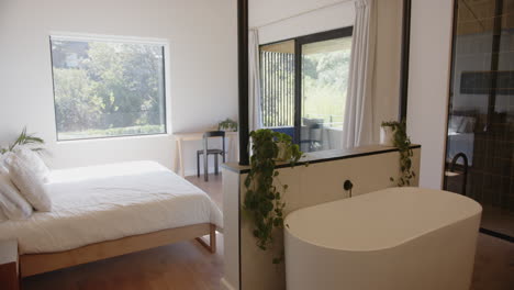 freestanding bathtub in modern bedroom with large window, creating serene atmosphere, copy space