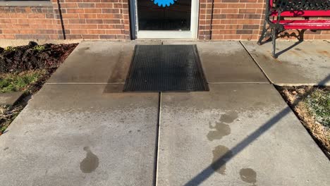 Black-floor-mat-on-cement-with-rain-drops-hitting-it