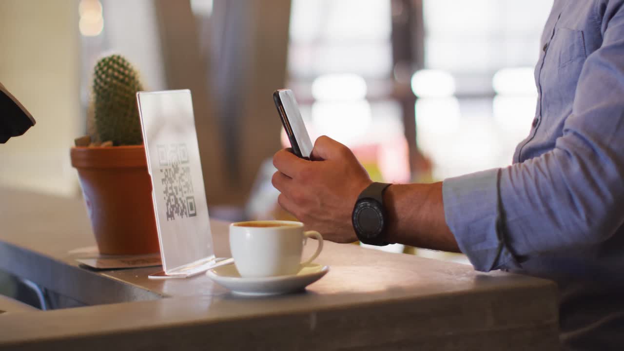 Mixed race man giving african american female cafe worker his smartphone in order to pay
