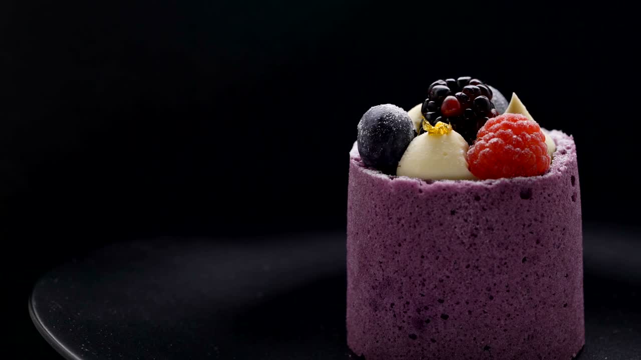 pasteles de mousse de bayas púrpuras con moras y frambuesas en un plato negro