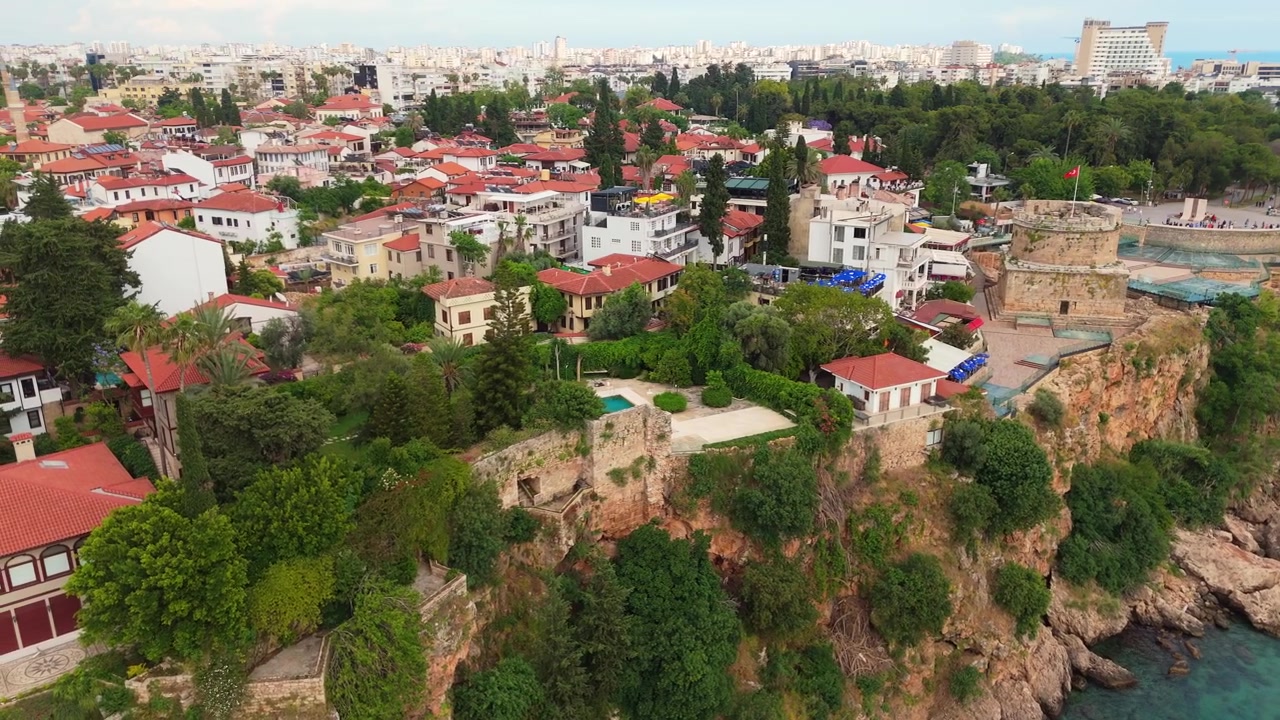 Vista aerea che sorvola il lussureggiante parco verde e le fortificazioni storiche sulle scogliere rocciose del quartiere della città vecchia di Kaleici, con vista sul mare aperto del Mediterraneo, Antalya, Turchia.