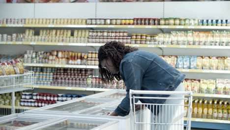 serious young customer choosing goods in freezer