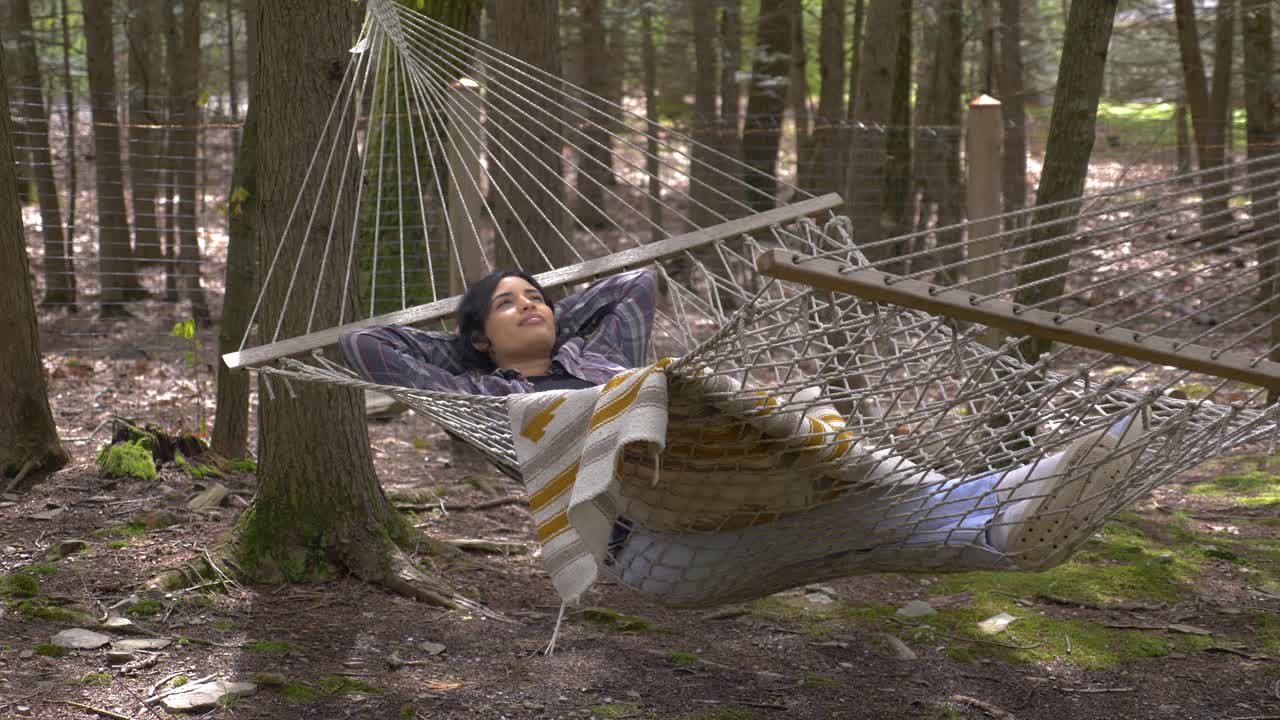 cómoda mujer puertorriqueña balanceándose en una hamaca del bosque soñando despierto pacíficamente