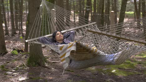 cómoda mujer puertorriqueña balanceándose en una hamaca del bosque soñando despierto pacíficamente