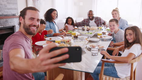 two families taking selfie as they enjoy meal at home together
