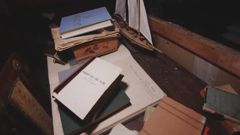old books and documents with ship replica on table in abandoned building in italy. handheld, tilt-down shot