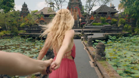 casal de viagem de mãos dadas excitado mulher líder namorado explorando templo de saraswati se divertindo turismo cultura de bali indonésia