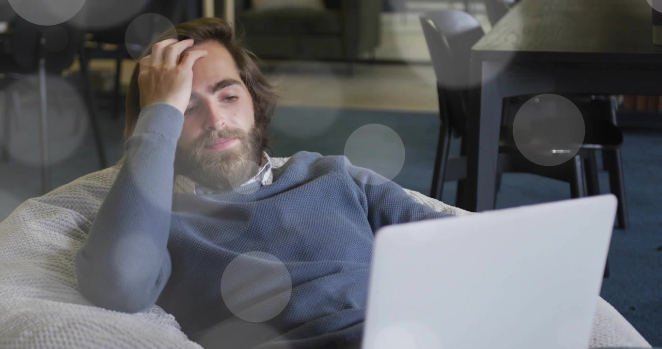 Man typing on laptop and activating overlays while tilting head and analyzing business data