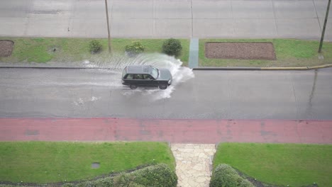 Geländewagen-Fährt-Auf-überfluteten-Straßen-Und-Spritzt-Wasser,-Handgeführt-Aus-Der-Vogelperspektive