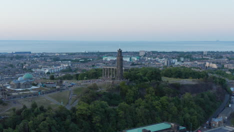 Toma-Aérea-De-Multitudes-Reunidas-En-Calton-Hill-En-Edimburgo-Con-El-Horizonte-De-La-Ciudad-Al-Fondo